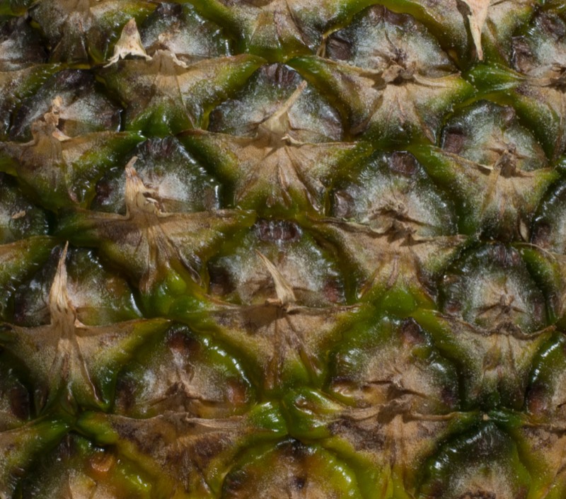 Close-up of pineapple skin with golden polygonal eyes and green edges